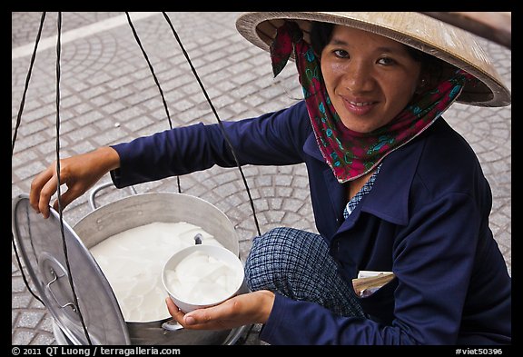 Woman smiling while handling bowl of soft tofu. Ho Chi Minh City, Vietnam (color)