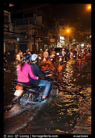Couple riding motorcycle on flooded street at night. Ho Chi Minh City, Vietnam