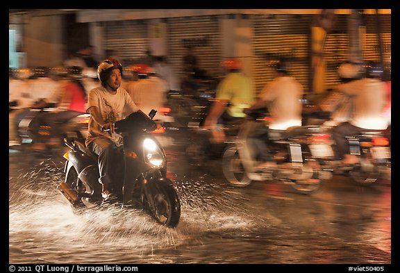 Man riding motorbike on flooded street seen against riders going in opposite direction. Ho Chi Minh City, Vietnam