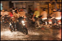 Man riding motorbike on flooded street seen against riders going in opposite direction. Ho Chi Minh City, Vietnam