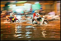 Motion-blured exposure of riders on flooded street at night. Ho Chi Minh City, Vietnam (color)