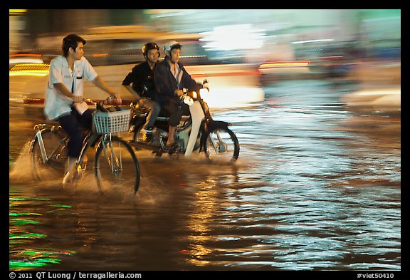 Bicyle and motorbike riders on monsoon-flooded street. Ho Chi Minh City, Vietnam (color)