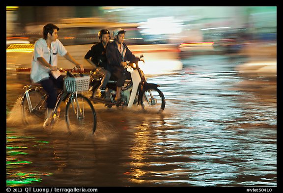 Bicyle and motorbike riders on monsoon-flooded street. Ho Chi Minh City, Vietnam