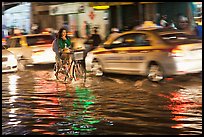 Women riding a bicycle on a flooded street at night. Ho Chi Minh City, Vietnam ( color)