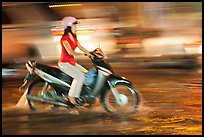 Woman riding on water-filled street, and light streaks. Ho Chi Minh City, Vietnam (color)