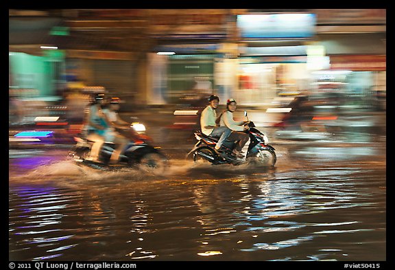 Motorcycles riding through the water on street with motion. Ho Chi Minh City, Vietnam (color)