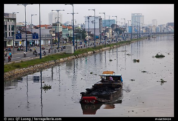 Barge with traditional painted eyes on Saigon Arroyau with backdrop of expressway traffic. Cholon, Ho Chi Minh City, Vietnam