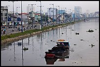 Barge with traditional painted eyes on Saigon Arroyau with backdrop of expressway traffic. Cholon, Ho Chi Minh City, Vietnam