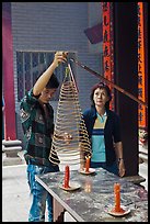 Man getting ready to hang incense coil, Thien Hau Pagoda, district 5. Cholon, District 5, Ho Chi Minh City, Vietnam (color)