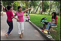 Young women dancing to sound of mobile phone, Cong Vien Van Hoa Park. Ho Chi Minh City, Vietnam ( color)