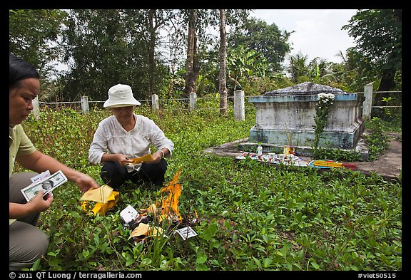 Women burning fake money as offering. Ben Tre, Vietnam (color)