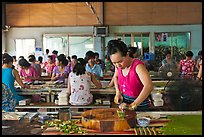 Woman cutting strips of coconut candy in factory. Ben Tre, Vietnam (color)