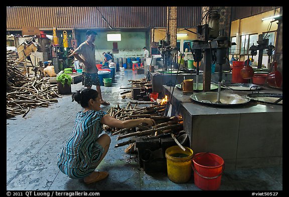 Woman feeding furnace in cococut candy factory. Ben Tre, Vietnam (color)