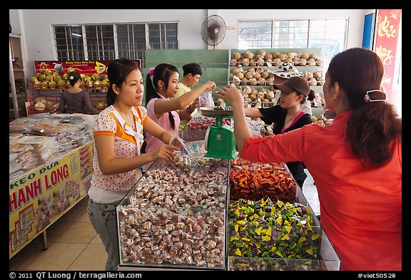 Women weighting coconut candy in retail store. Ben Tre, Vietnam