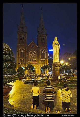 Family in prayer outside Notre-Dame Basilica at night. Ho Chi Minh City, Vietnam (color)