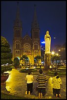 Family in prayer outside Notre-Dame Basilica at night. Ho Chi Minh City, Vietnam