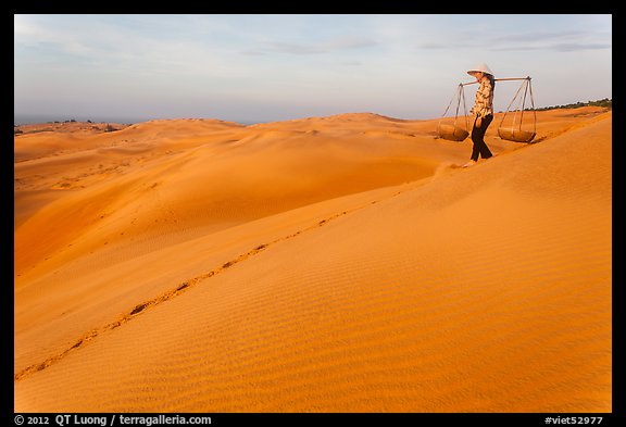 Woman descending sandhill with pannier baskets. Mui Ne, Vietnam (color)