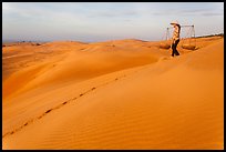 Woman descending sandhill with pannier baskets. Mui Ne, Vietnam ( color)