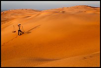 Red sand dunes and woman with carrying pole and baskets. Mui Ne, Vietnam (color)