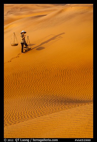 Woman with yoke baskets on sands. Mui Ne, Vietnam (color)