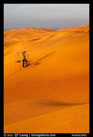 Rippled red sand dunes and woman with baskets. Mui Ne, Vietnam