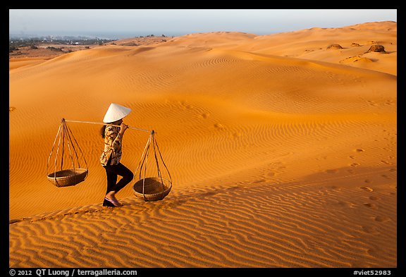 Woman carrying two baskets on shoulder pole. Mui Ne, Vietnam (color)