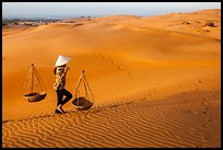 Woman carrying two baskets on shoulder pole. Mui Ne, Vietnam ( color)