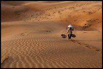 Woman with conical hat carries pannier baskets. Mui Ne, Vietnam ( color)