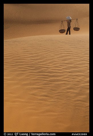 Figure with conical hats and two baskets on sand dunes. Mui Ne, Vietnam