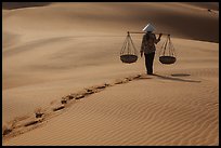 Woman walking on sand with two shoulder baskets. Mui Ne, Vietnam ( color)