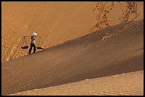 Woman ascending dune ridge with two baskets. Mui Ne, Vietnam ( color)