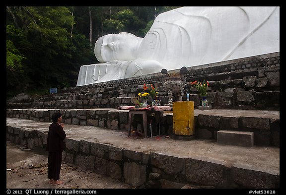 Woman prays below reclining Buddha statue. Ta Cu Mountain, Vietnam