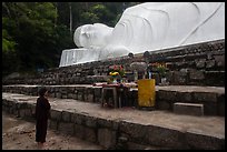 Woman prays below reclining Buddha statue. Ta Cu Mountain, Vietnam (color)