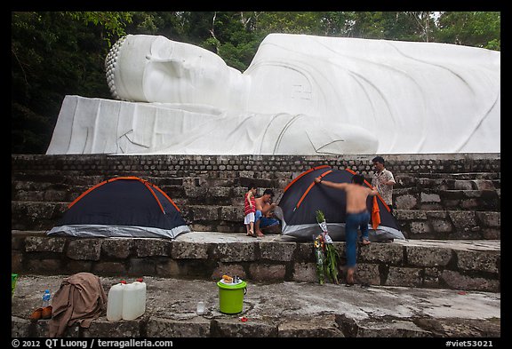 Pilgrims pitch tent below reclining Buddha statue. Ta Cu Mountain, Vietnam