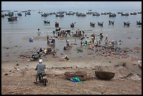 Man on motorbike looks over beach and harbor. Mui Ne, Vietnam (color)