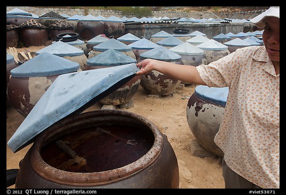 Woman examining vat of fish sauch. Mui Ne, Vietnam (color)