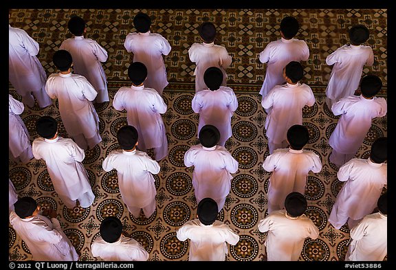 Worshippers dressed in white stand in rows in Cao Dai temple. Tay Ninh, Vietnam