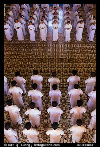 Men and women dressed in white stand in opposing rows in Cao Dai temple. Tay Ninh, Vietnam (color)