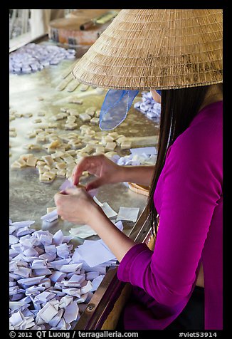 Woman wearing conical hat wrapping coconut candy, Phoenix Island. My Tho, Vietnam (color)