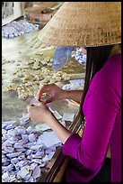 Woman wearing conical hat wrapping coconut candy, Phoenix Island. My Tho, Vietnam (color)