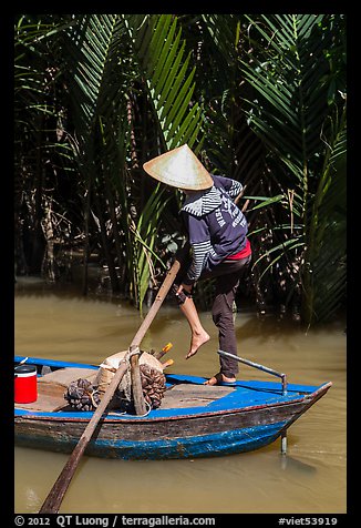 Woman standing in canoe on jungle canal, Phoenix Island. My Tho, Vietnam