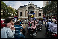 Families gather on motorbikes to watch performance in front of opera house. Ho Chi Minh City, Vietnam (color)