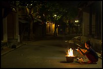Woman burning paper on street at night. Hoi An, Vietnam ( color)