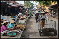 Woman pushing cart on market street. Hoi An, Vietnam ( color)