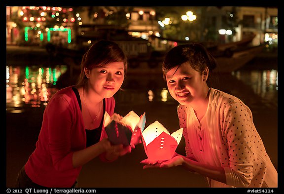 Two women lighted by candle box at night. Hoi An, Vietnam (color)