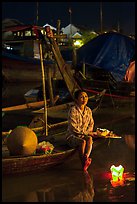 Woman sitting in boat with floating candles by night. Hoi An, Vietnam ( color)