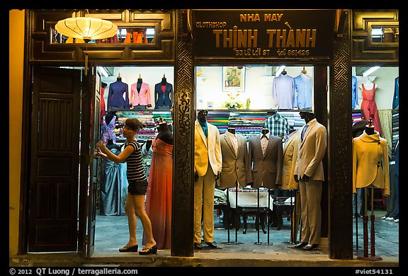 Woman closing doors of taylor shop. Hoi An, Vietnam (color)