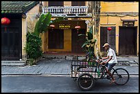 Man riding tricycle cart in front of old townhouses. Hoi An, Vietnam (color)