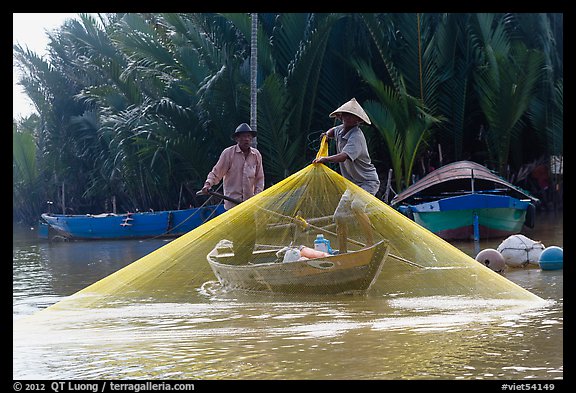 Fisherman pulls up net from rowboat. Hoi An, Vietnam (color)