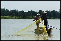 Fishermen standing in boat retrieving net, Thu Bon River. Hoi An, Vietnam (color)